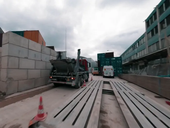 A skip truck carrying a skip on a sorting platform, still from the Nereva film